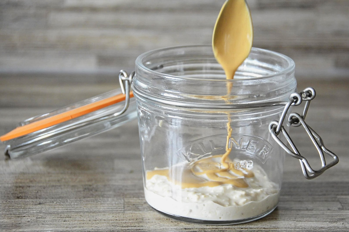 Beginning to layer oats and peanut butter swirl in bottom of glass kilner jar