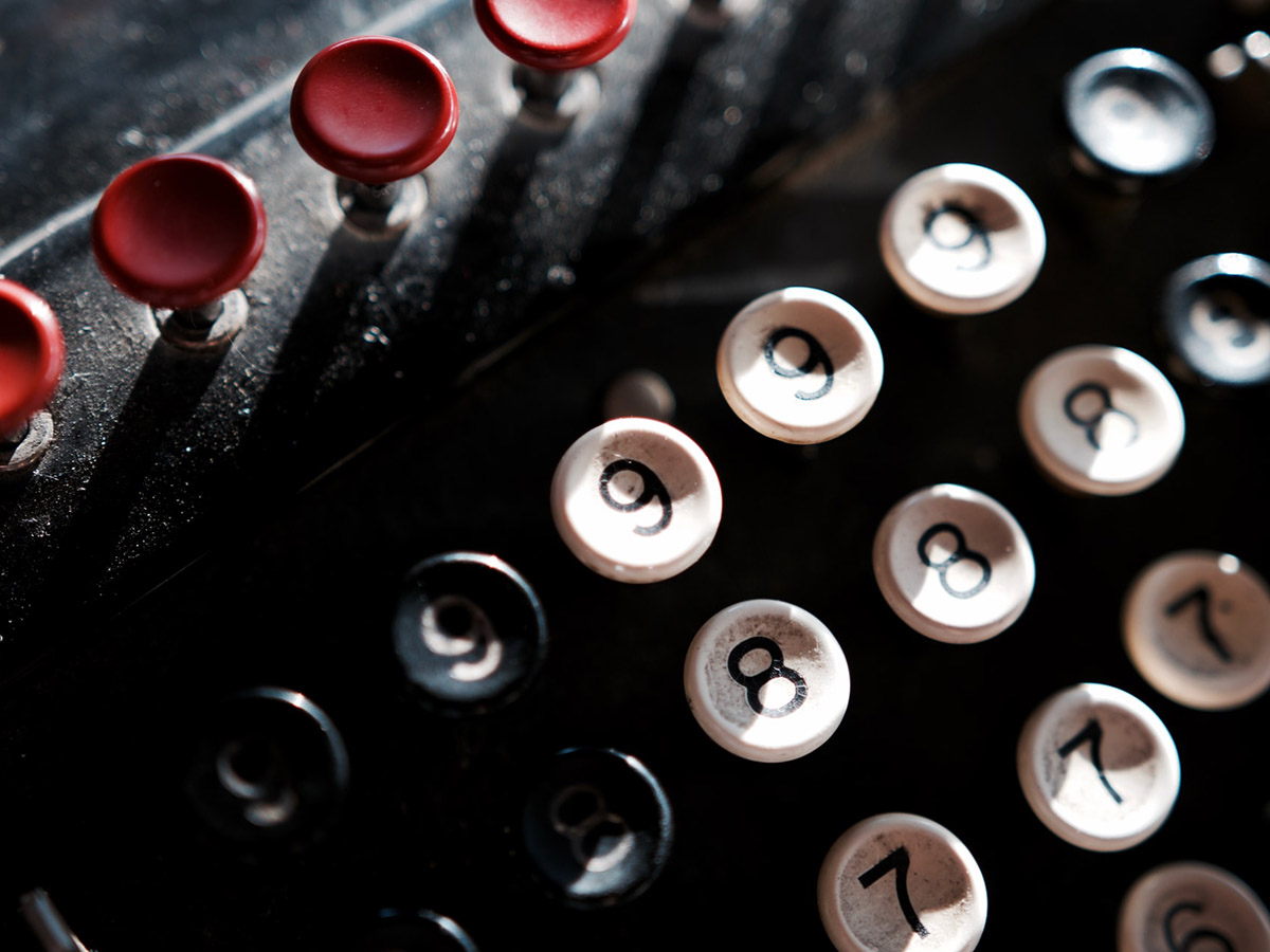 Old machinery with round numbered buttons only 6 to 9 visible beneath a row of red buttons