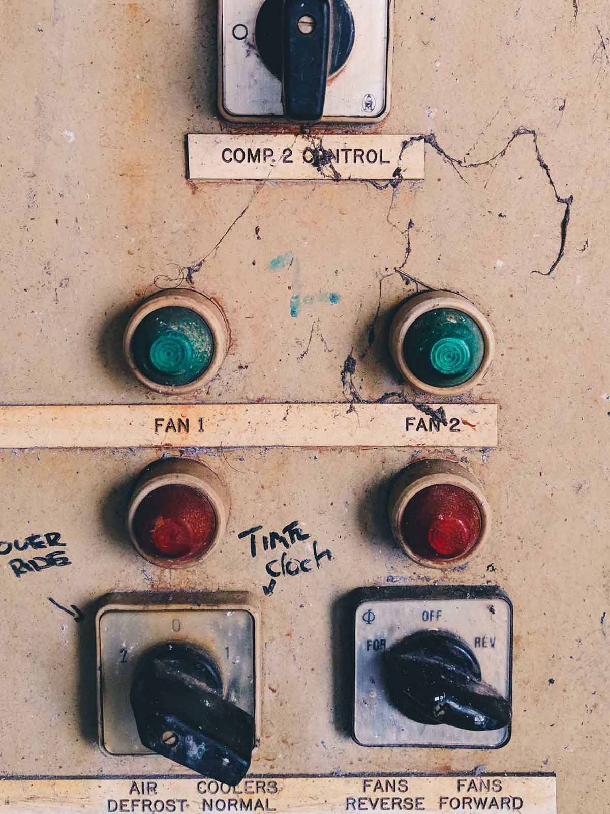 red and green bulbs beside dials on an old, paint splattered control panel