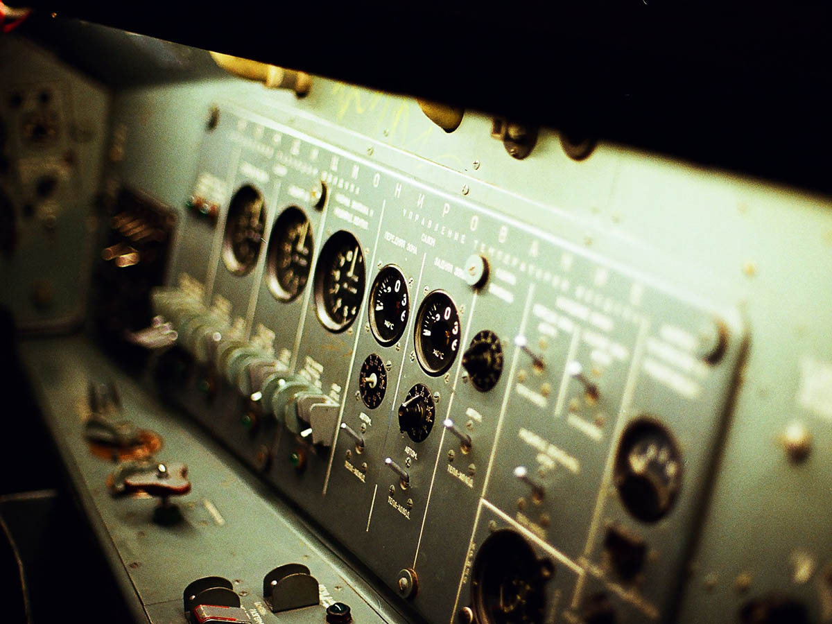 Old fashioned looking industrial control panel featuring multiple switches and dials alongside Russian lettering.