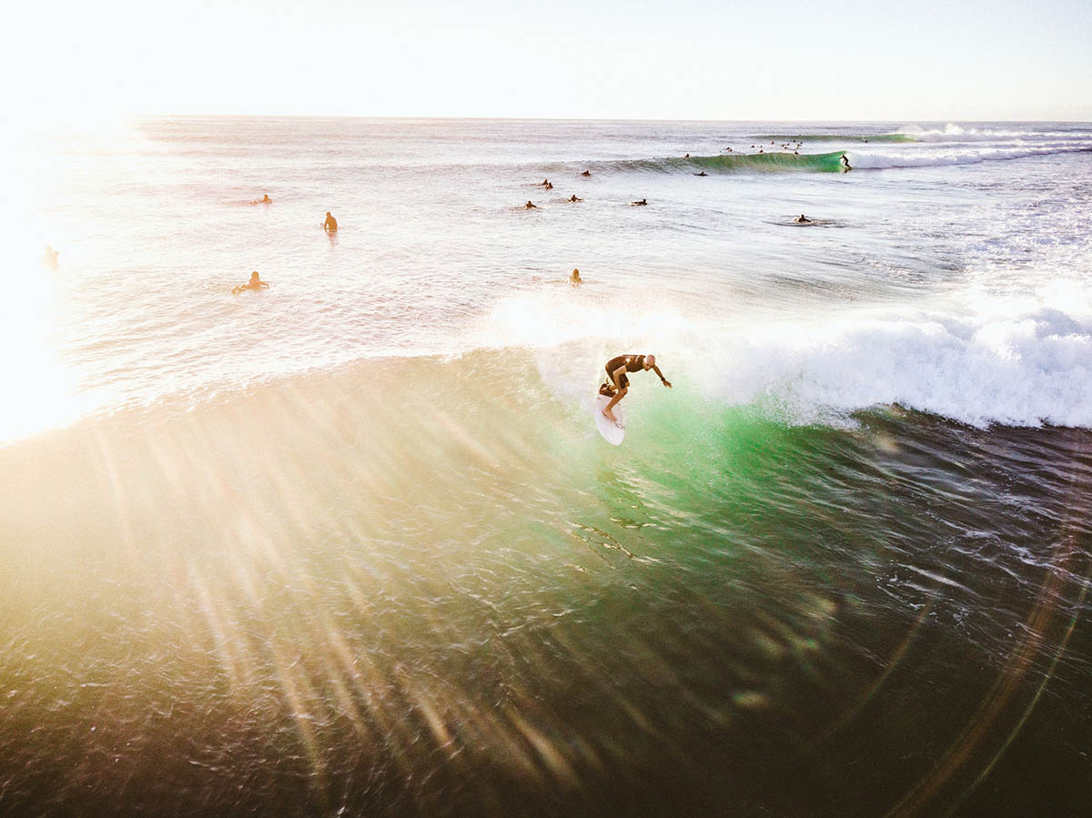Surfer riding a small crest towards shore as other surfers look on.