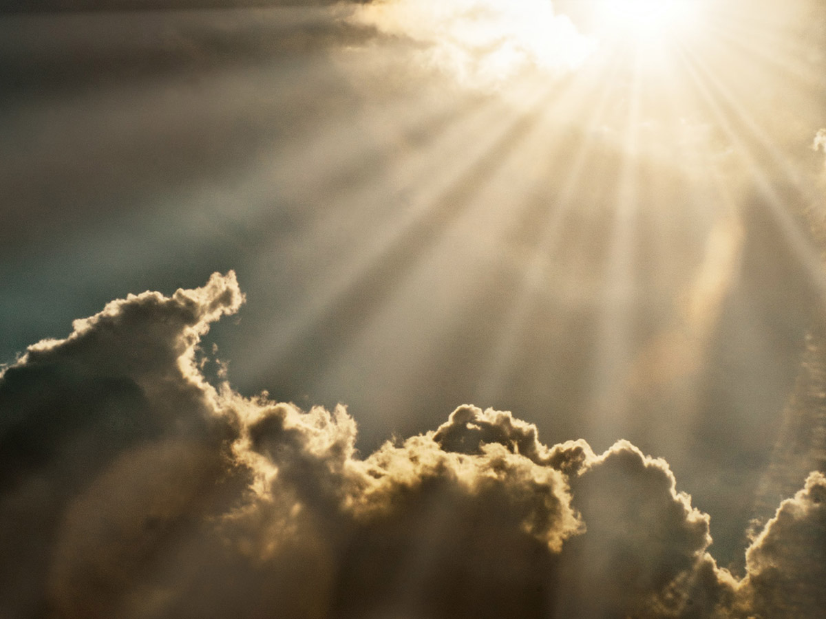 Rays of sunlight illuminating dark and moody clouds from above.