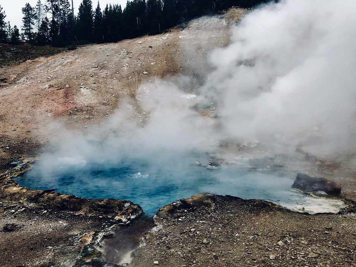Steaming hot pool in a rocky landscape.