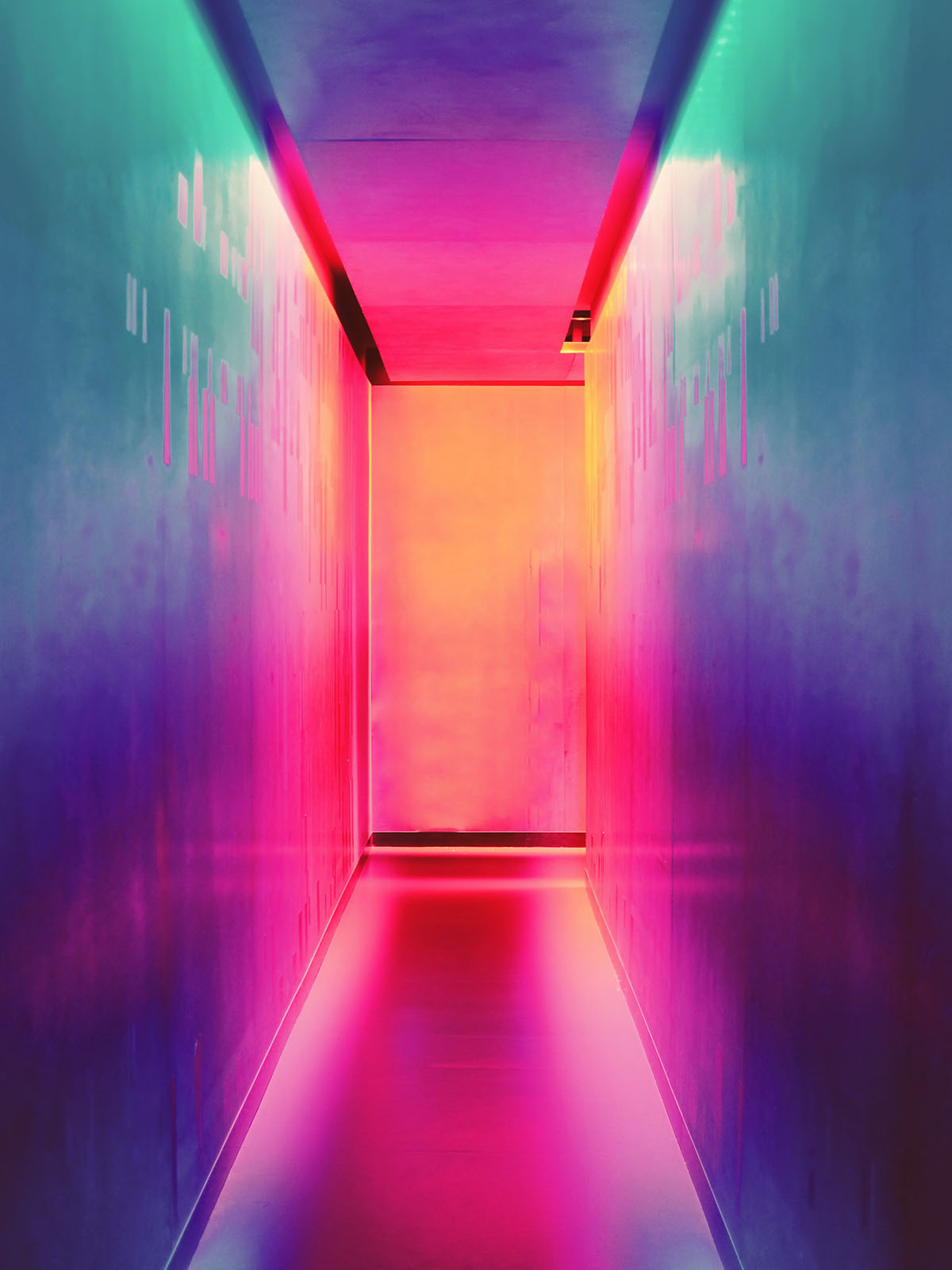 Rainbow coloured illuminated hallway receding into distance.