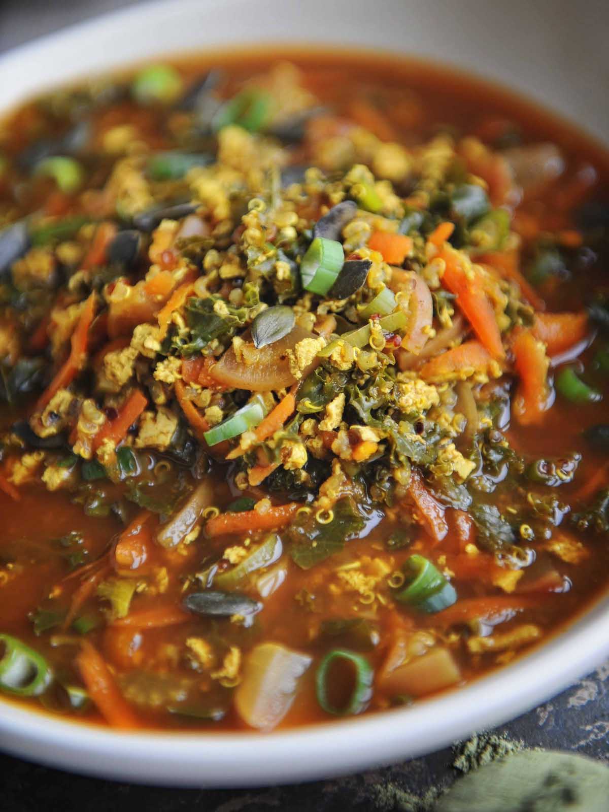 Close up of rich, vegetable, tofu and quinoa filled broth.